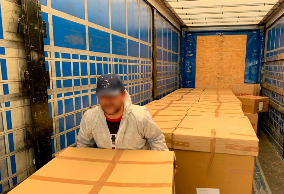 Empleado en un camión de carga con cajas apiladas.