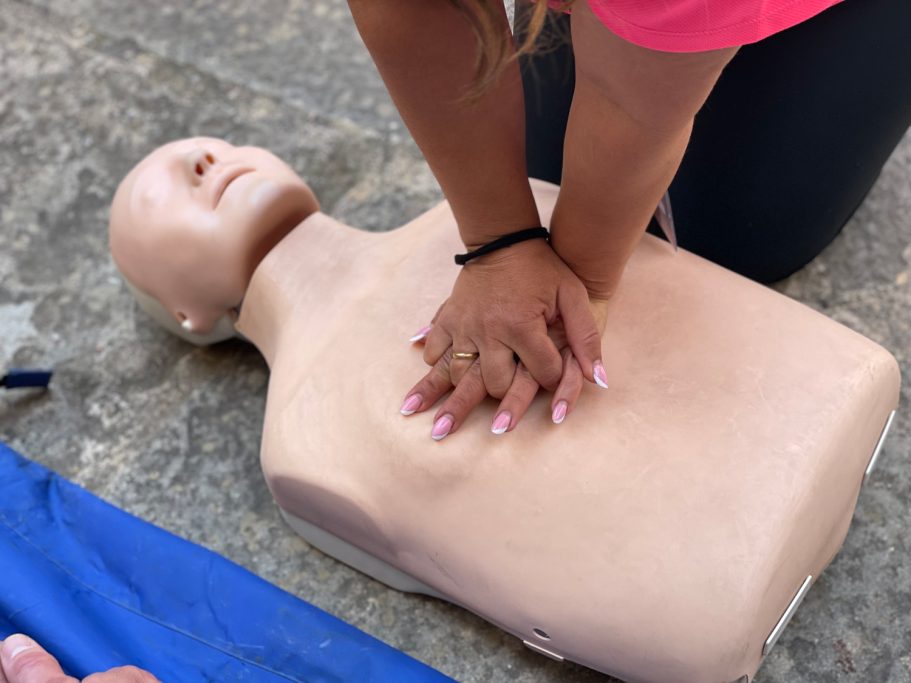 Mujer practica RCP en un maniquí en el suelo. Se muestra la colocación de las manos.