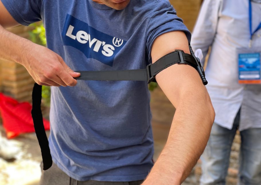Una persona se ajusta un torniquete táctico en el brazo, mientras otras personas observan.