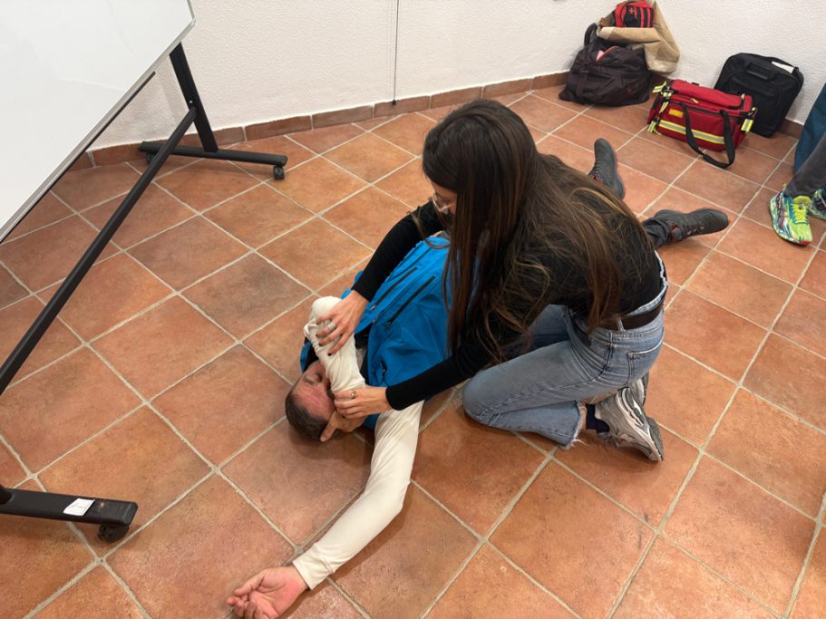 Una mujer realiza maniobras de primeros auxilios sobre una persona en el suelo.