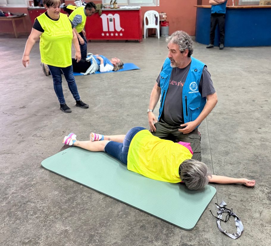 Personas en una sala de entrenamiento, junto a otra que está recibiendo primeros auxilios en el suelo.