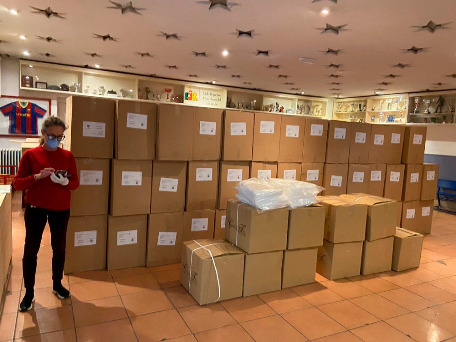Mujer de pie junto a una gran cantidad de cajas apiladas en un espacio interior.