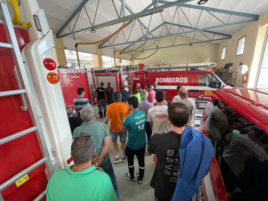 Grupo de personas en una estación de bomberos observando vehículos y equipos.
