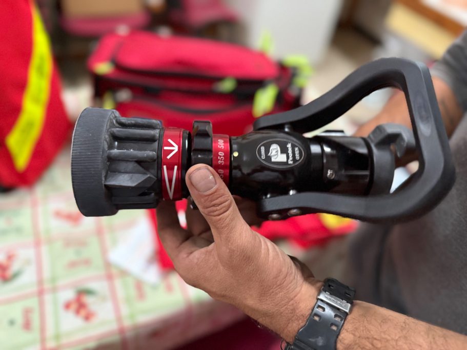 Una persona sostiene una boquilla de manguera de agua con un diseño especializado para incendios.
