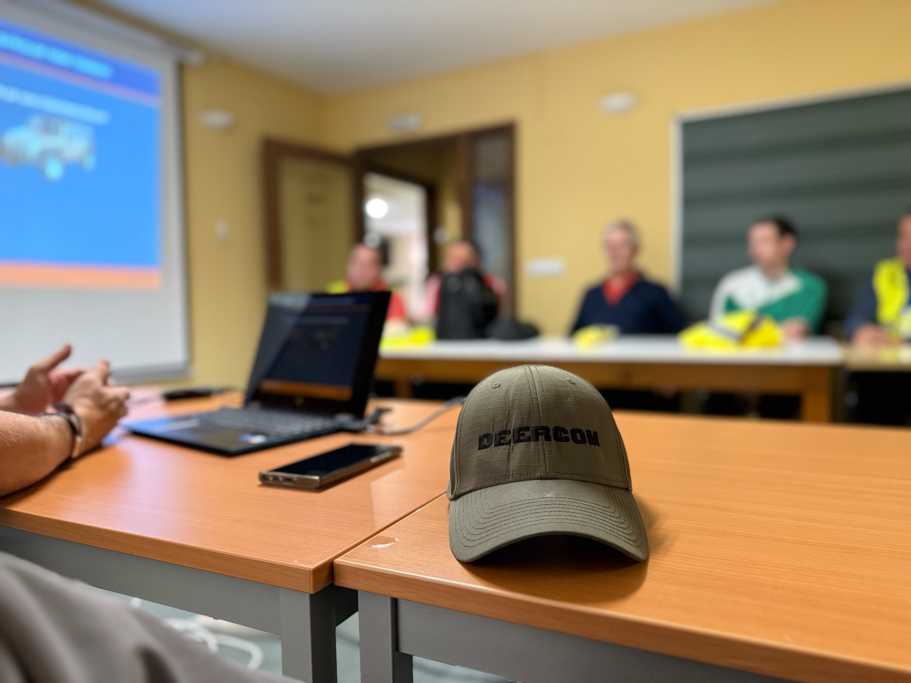 Reunión en aula con personas sentadas y un ordenador portátil sobre la mesa.