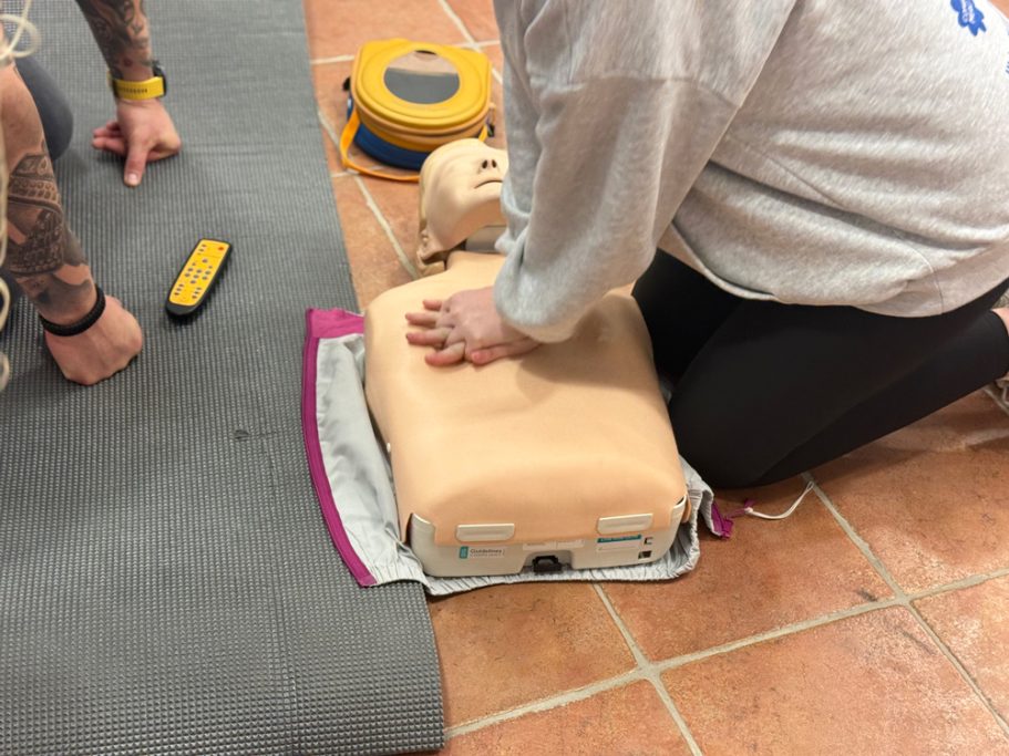 Una persona realizando RCP en un muñeco de entrenamiento en una superficie de goma.