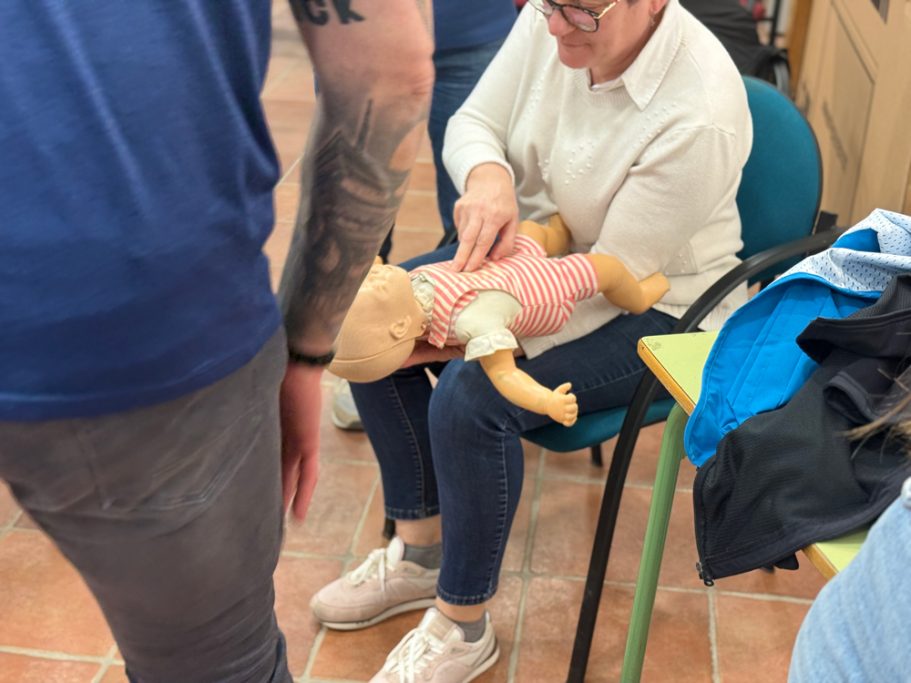 Mujer realizando maniobras RCP a un muñeco bebé.