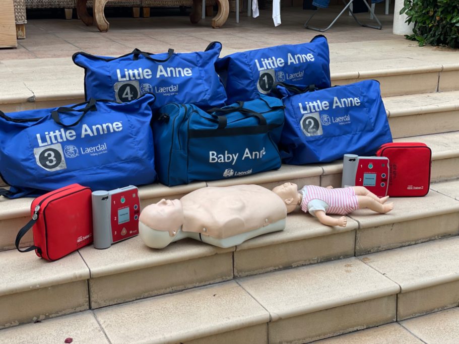 Bolsas de entrenamiento en primeros auxilios junto a muñecos y desfibriladores.