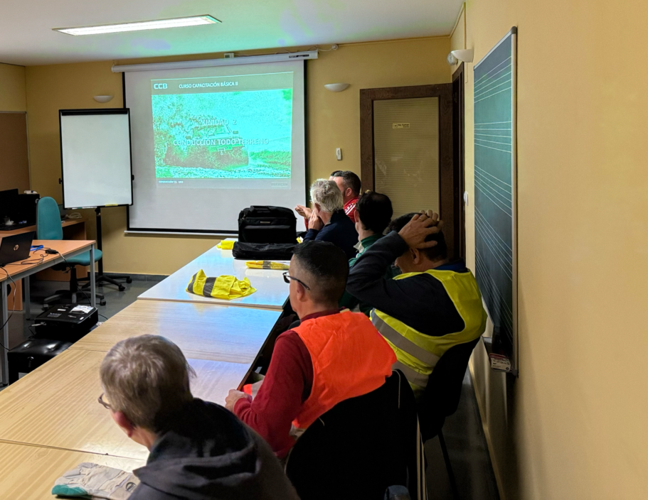 Grupo de personas en una sala de reuniones, mirando una presentación en pantalla.