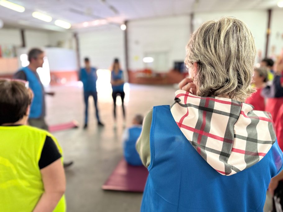 Grupo de personas en un taller, algunos con chalecos coloridos, escuchando a un instructor.